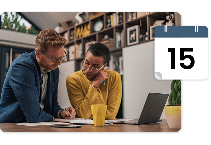 Two people in an office setting, looking at a laptop and notes. A calendar icon shows the number 15.